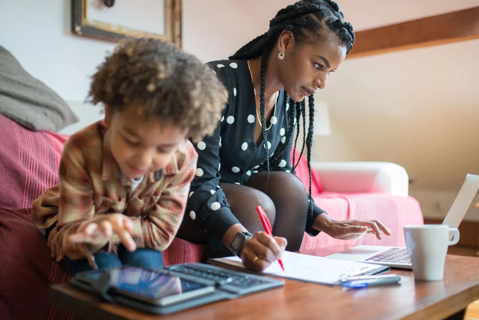 Mamá trabajando en su laptop mientras su hijo juega al lado