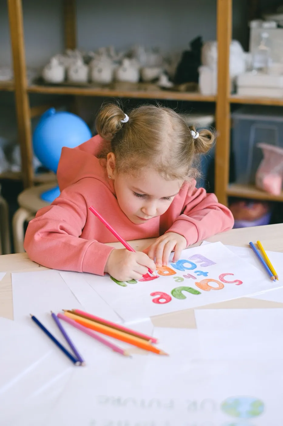 Niña dibujando con lápices de colores en un taller